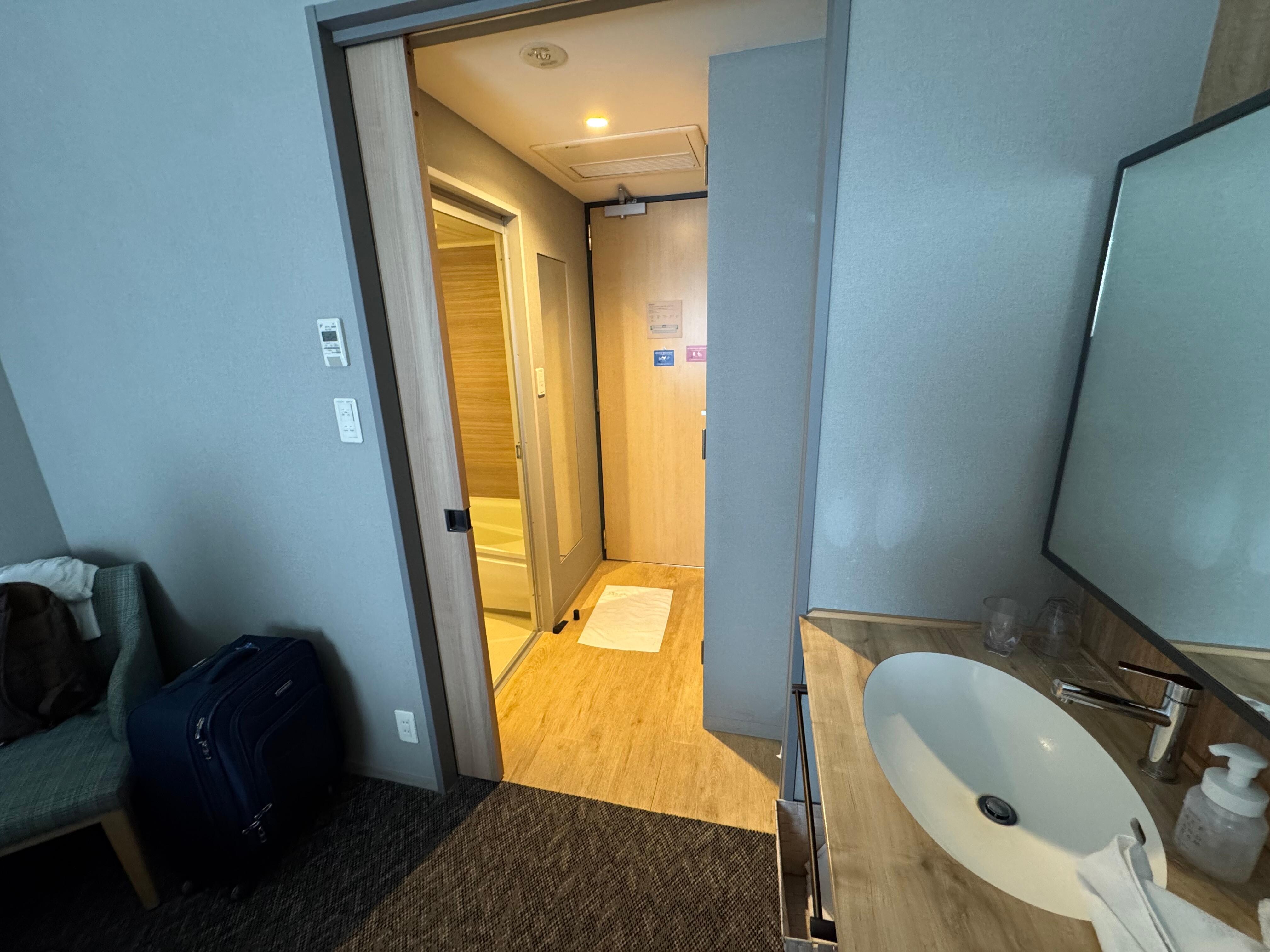 Looking from bedroom through bathroom to door. Toilet has separate privacy door