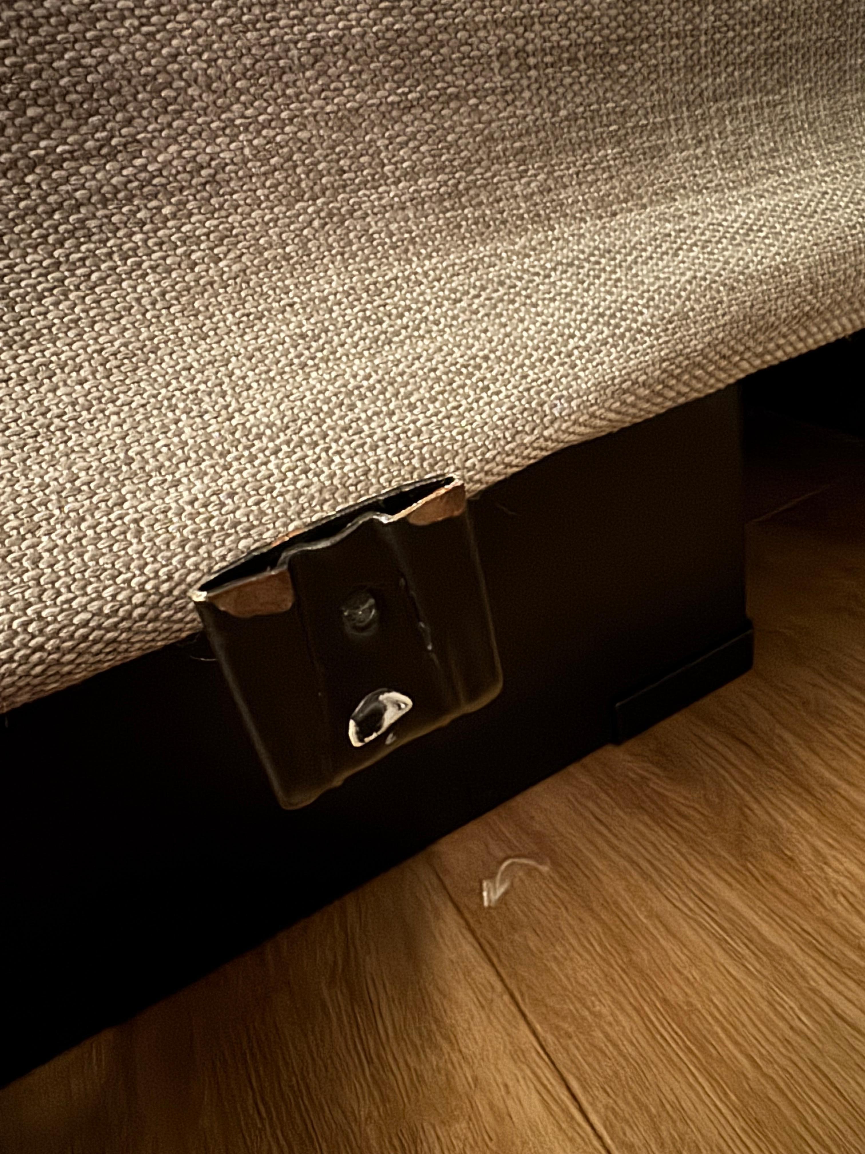 Sharp rusted metal slats protruding from under the bed. The mattress is intended to sit within these, but the mattress is too small, leaving three of these sharp rusty hooks at ankle height on either side of the bed.