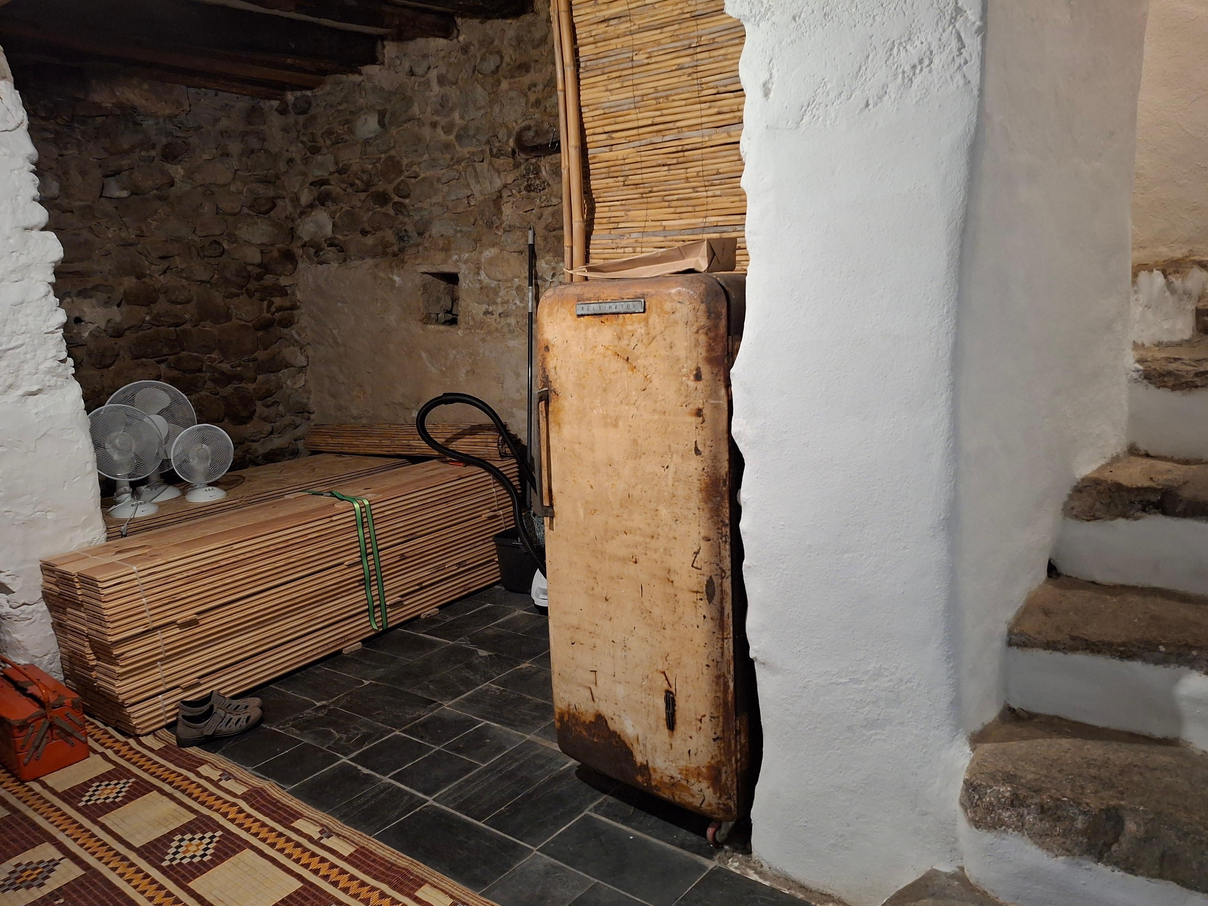 Alter, verrosteter  ausrangierter Kühlschrank; angeblich eine Theaterrequisite, wofür uns aber jeglicher Kunstsinn abginge, dies zu erkennen; im Hintergrund lagert Bauholz