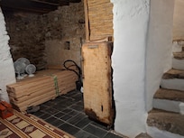 Alter, verrosteter ausrangierter Kühlschrank; angeblich eine Theaterrequisite, wofür uns aber jeglicher Kunstsinn abginge, dies zu erkennen; im Hintergrund lagert Bauholz