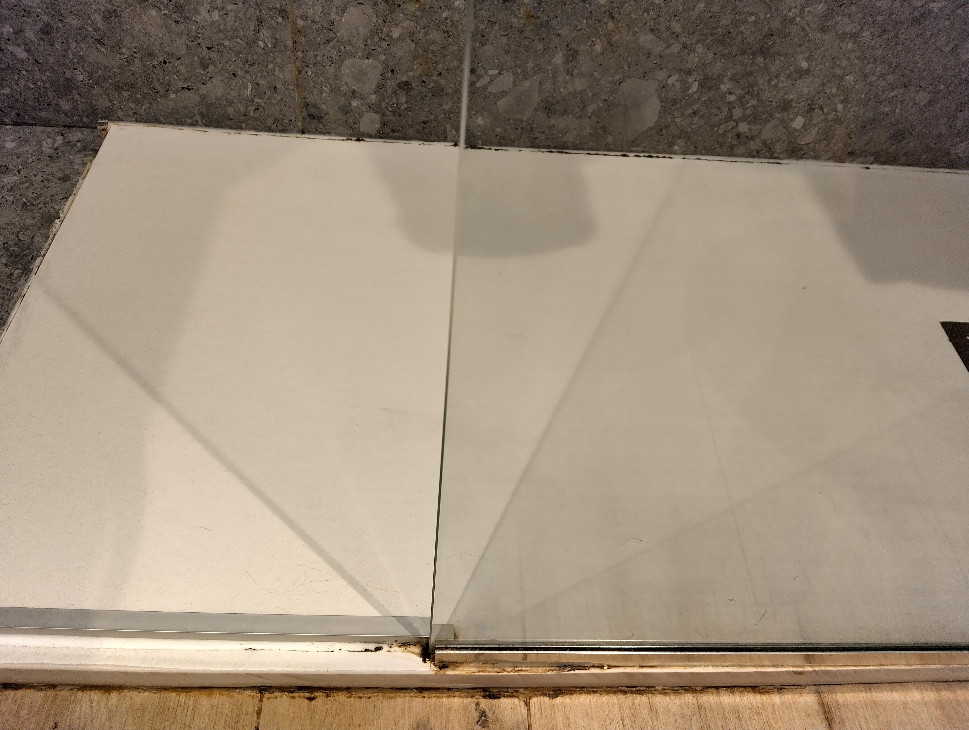 Mould and scum/dirt build-up around base perimeter of shower.