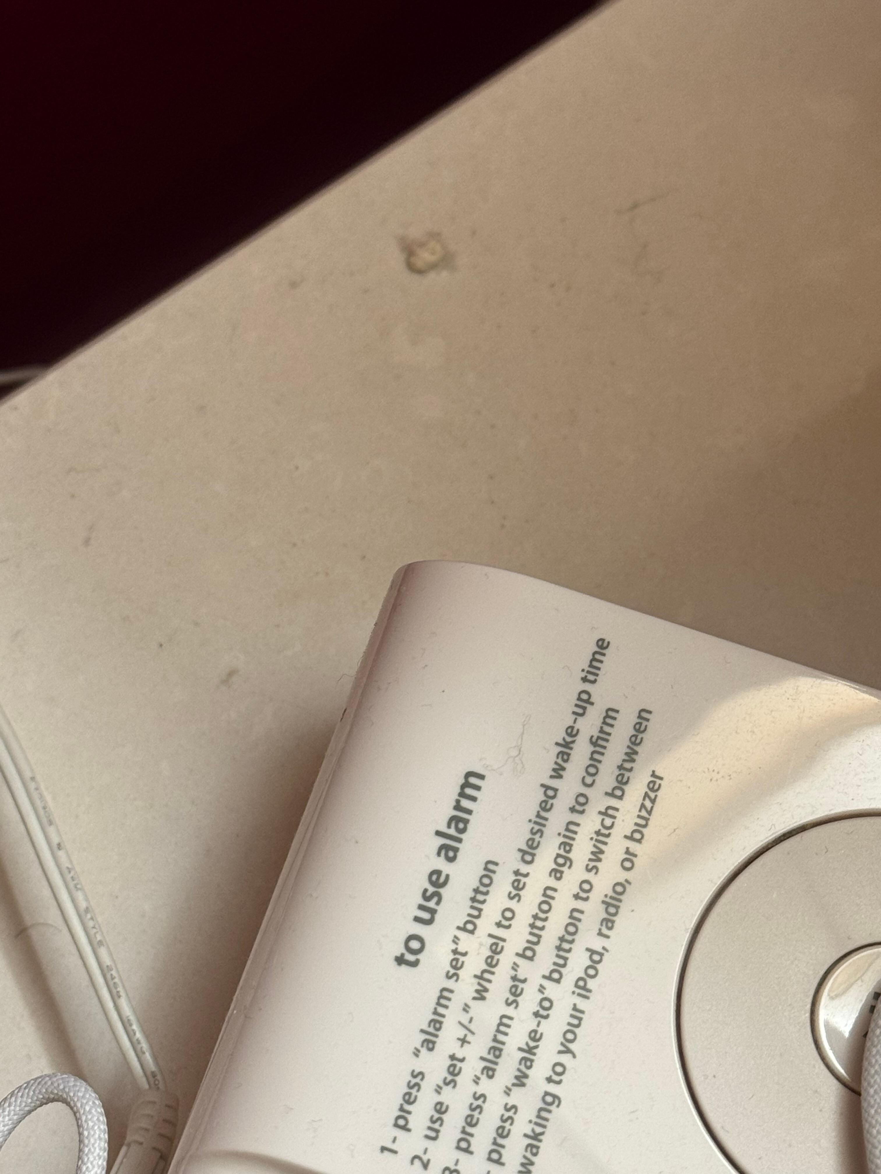 Dirty bedside table surface behind the clock. 