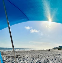 Sitting under the provided beach canopy.