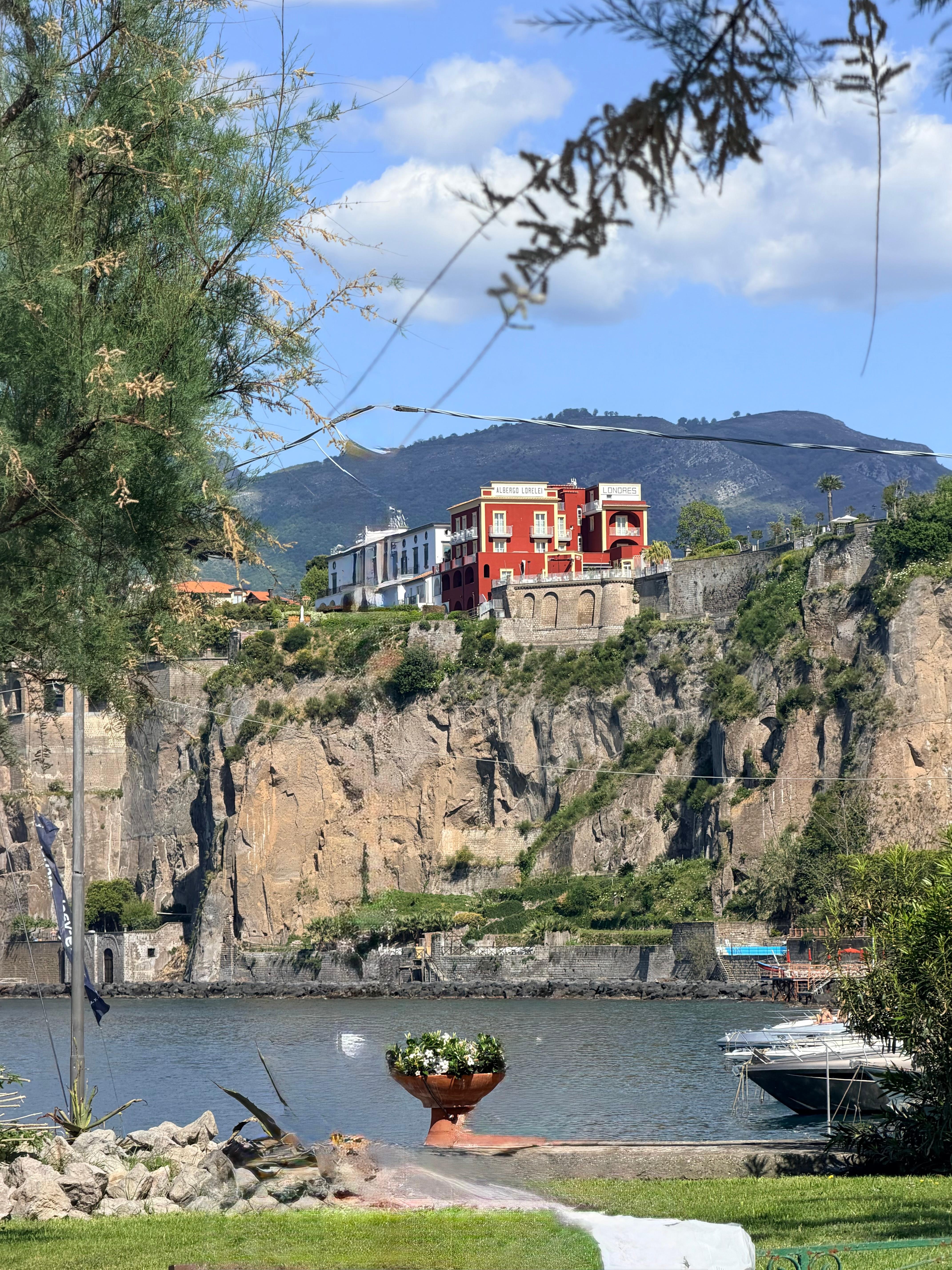 The rust colored building on the cliff.