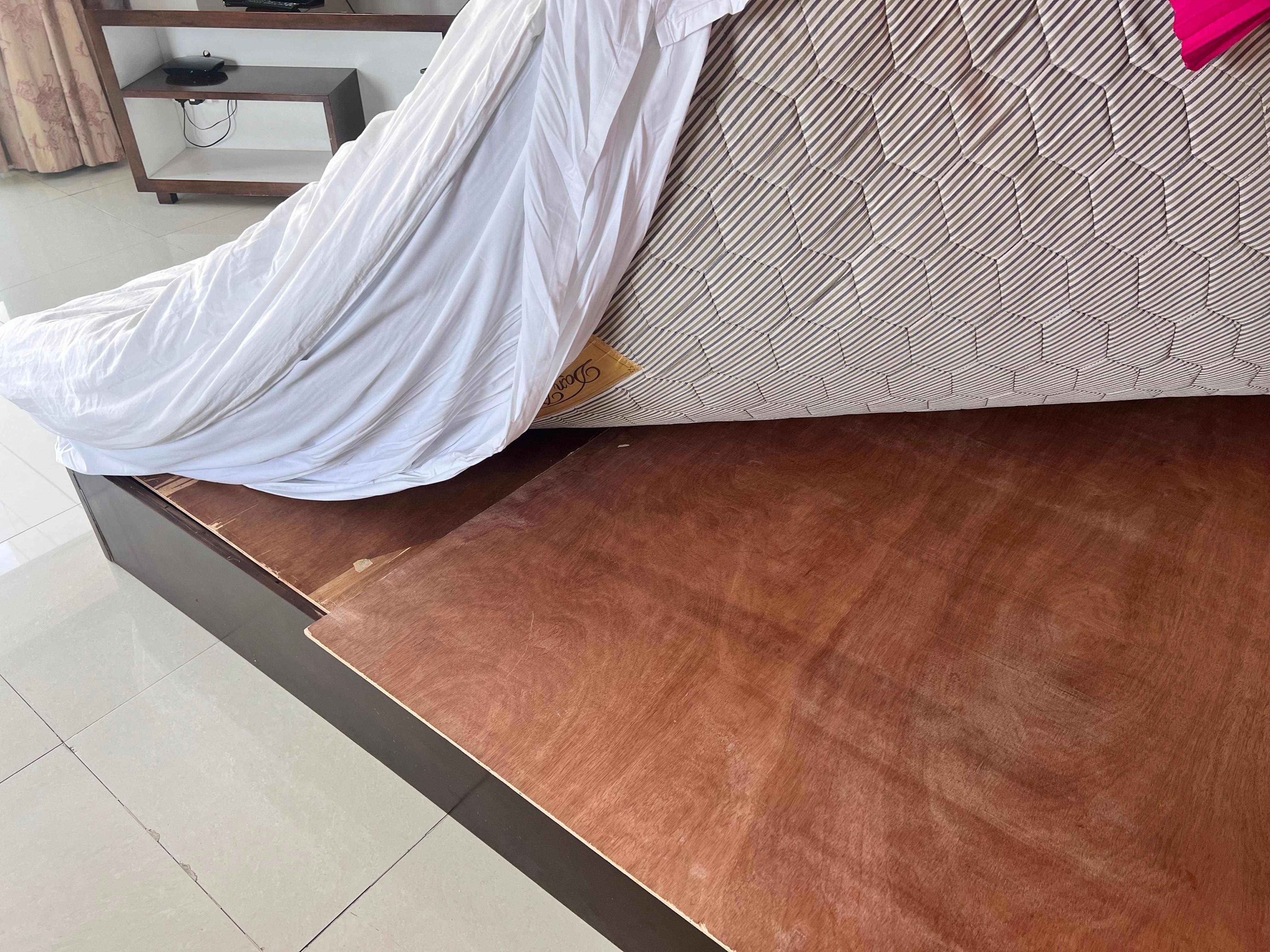 Very old mattress with cheap bed covered with plywood 