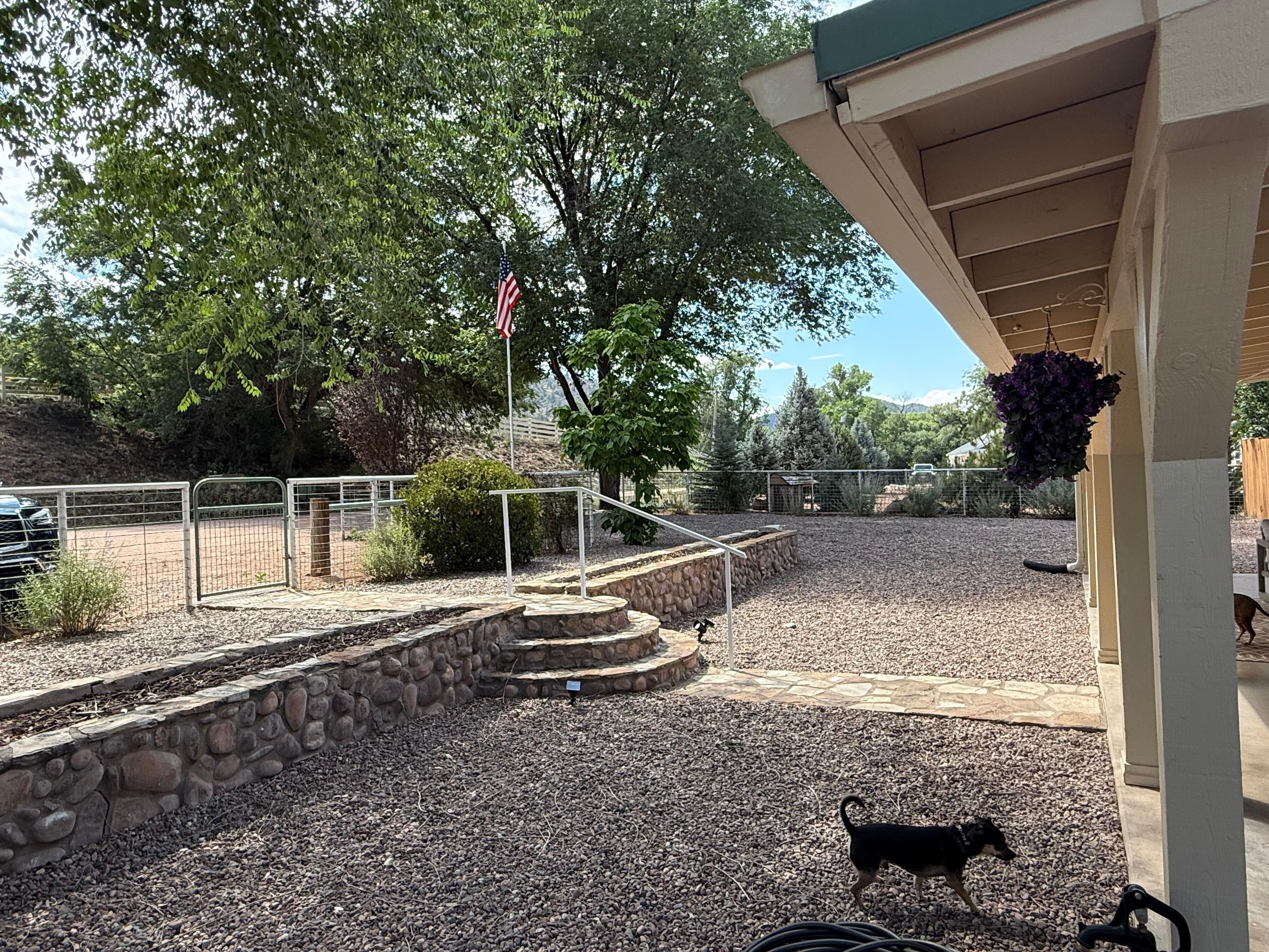 Expansive fenced front yard, with gate leading from parking and a path to the front door. 