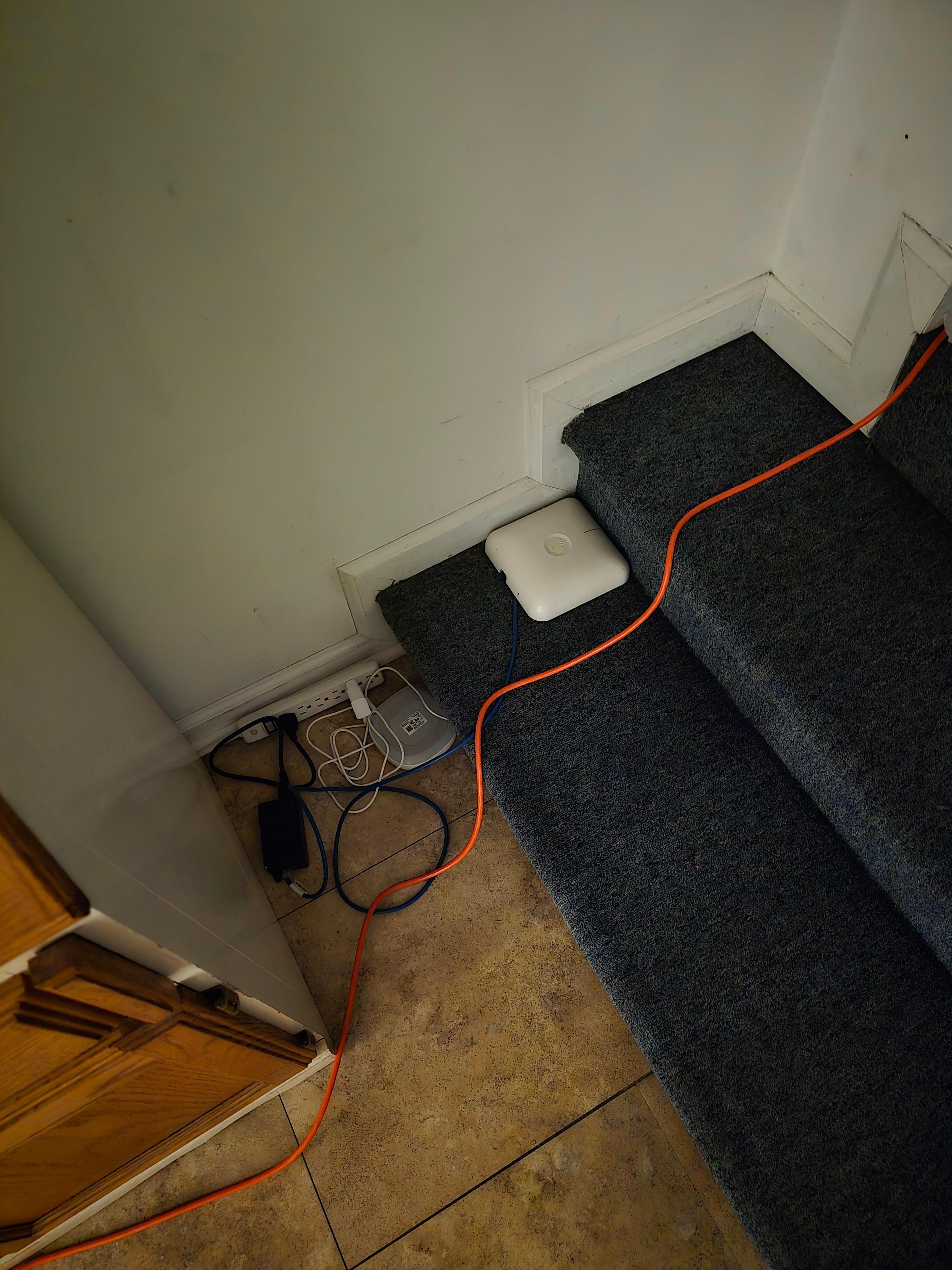 Bunches of cords for internet and a/c unit on steps from hallway to master.