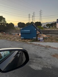 Dumpster overflowing right across from the entrance to a room