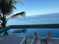 On comfy deck chair overlooking infinity pool out to the sea.
