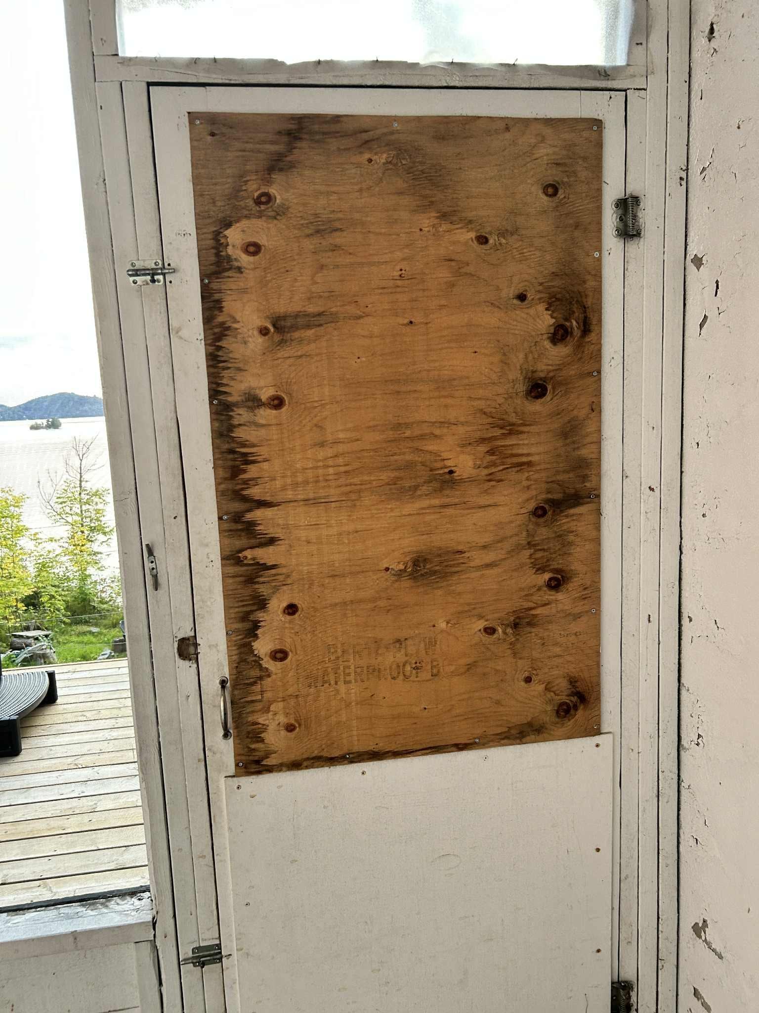 Boarded up door in screened in sitting area