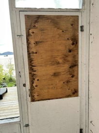 Boarded up door in screened in sitting area
