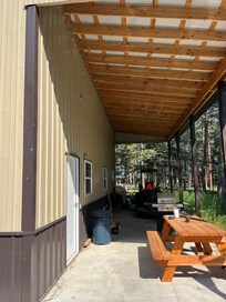 Grill and picnic table are under the carport that has a nice breeze