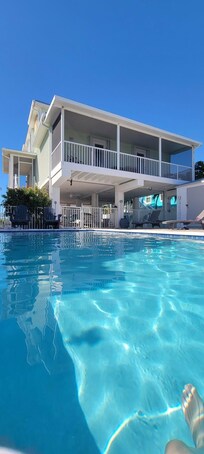 In Pool looking back at house rental (shows screened deck with 2 doors into 2 bedrooms).