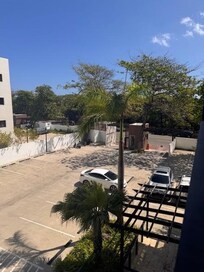 View from the balcony facing the street - the apartment is described as oceanfront - the ocean is across the street beyond the trees