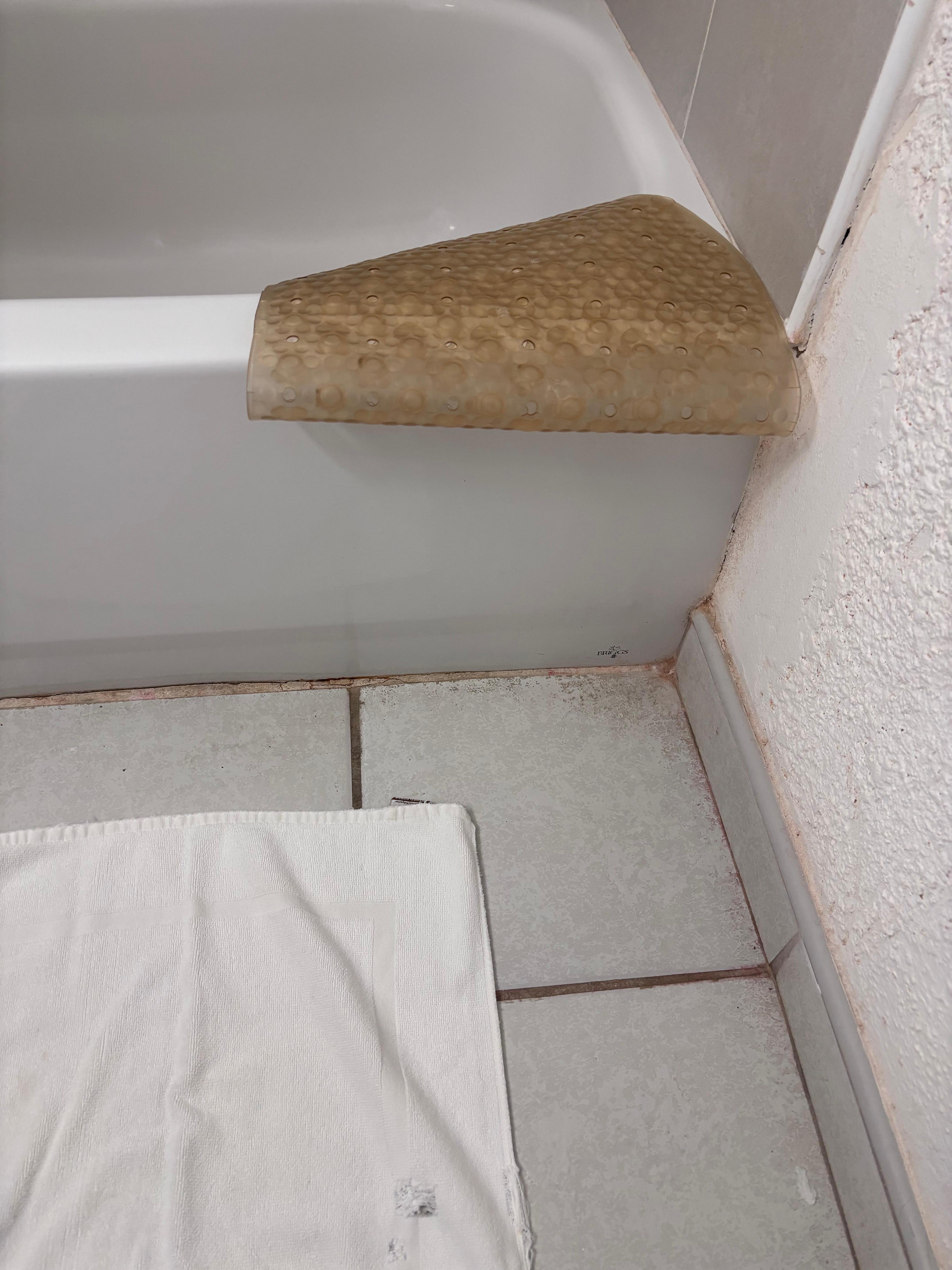 The yellow shower mat and bath mat with a hole. 