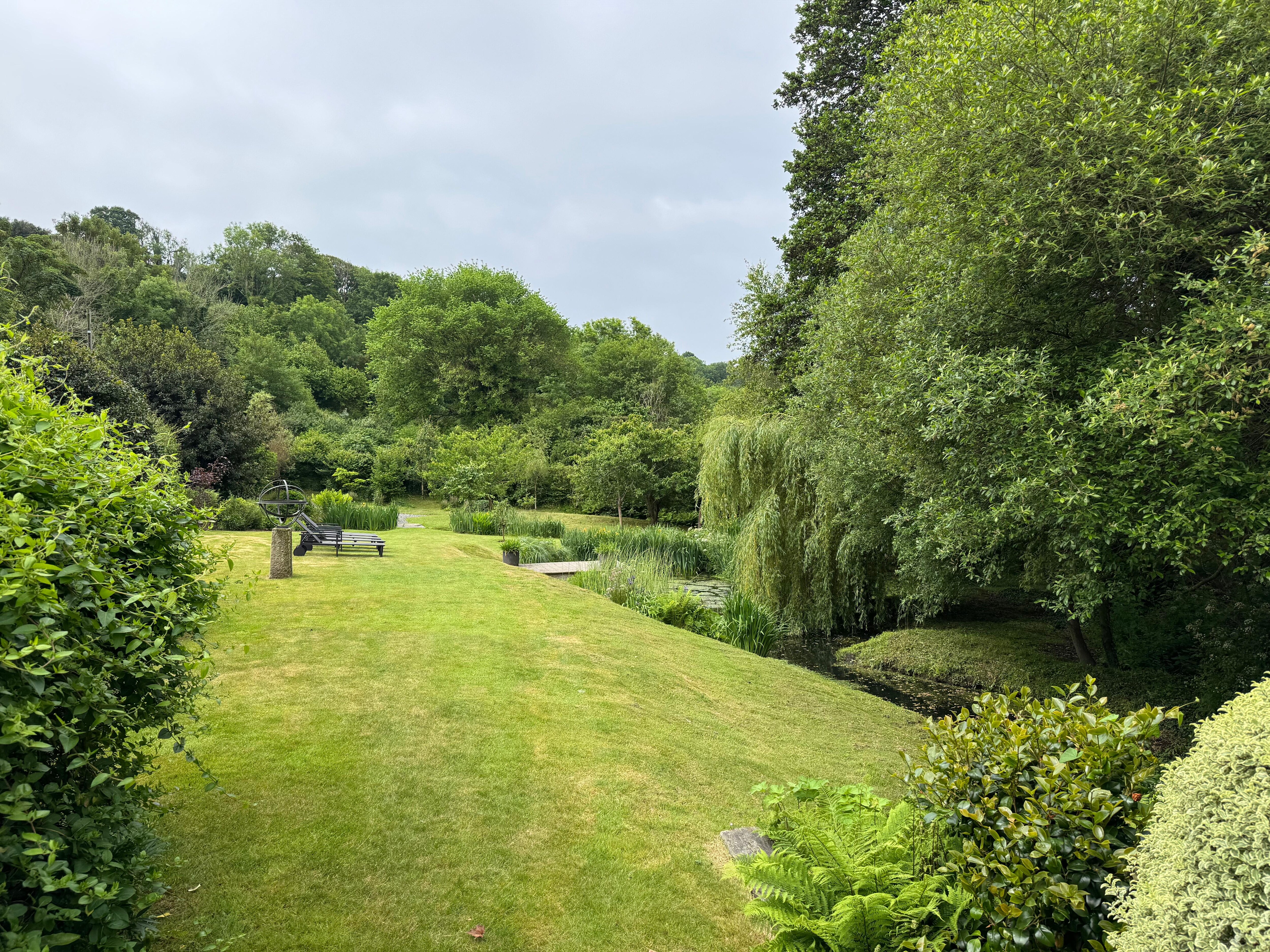 Large lawn with sun loungers, and pond 