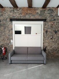 Couch, die als Bett aus der Wand klappt.