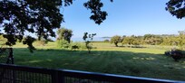 Blick vom Waldgarten über den Zaun und das Nachbargrundstück zum Bodden