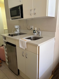 Cute little kitchenette with pots, pans, fridge, two burner stove top, plates, bowls, drink ware. Which is great if you’re on a spending budget.