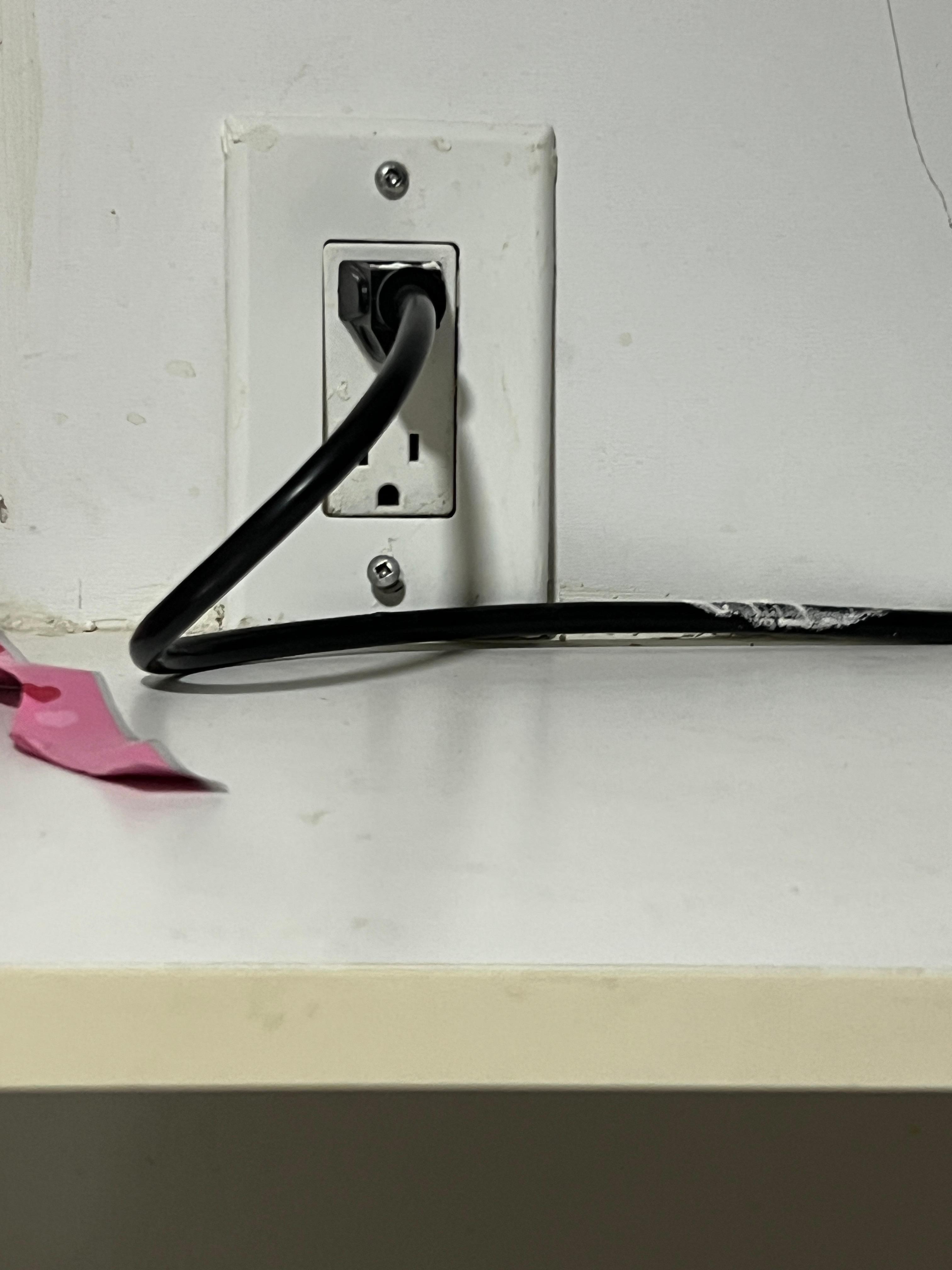 Cabinet in kitchen with no door. Has microwave plugged into loose tilted outlet